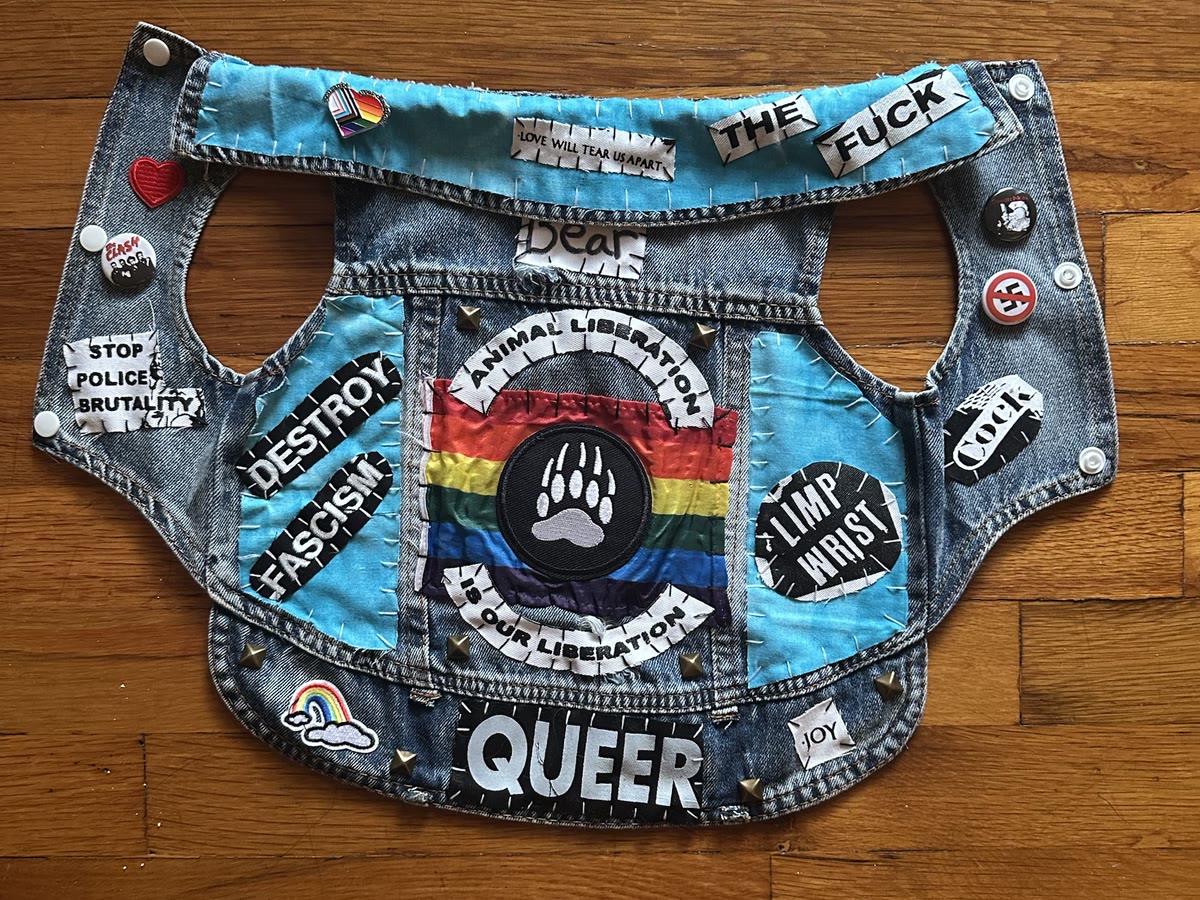 The Bear vest laid flat: a hand-lettered Bear strip at the collar, rainbow Animal Liberation Is Our Liberation back piece with a bear paw, a Queer patch along the hem, Destroy Fascism, Stop Police Brutality, Limp Wrist, Love Will Tear Us Apart and Joy patches, turquoise panels, studs and pins
