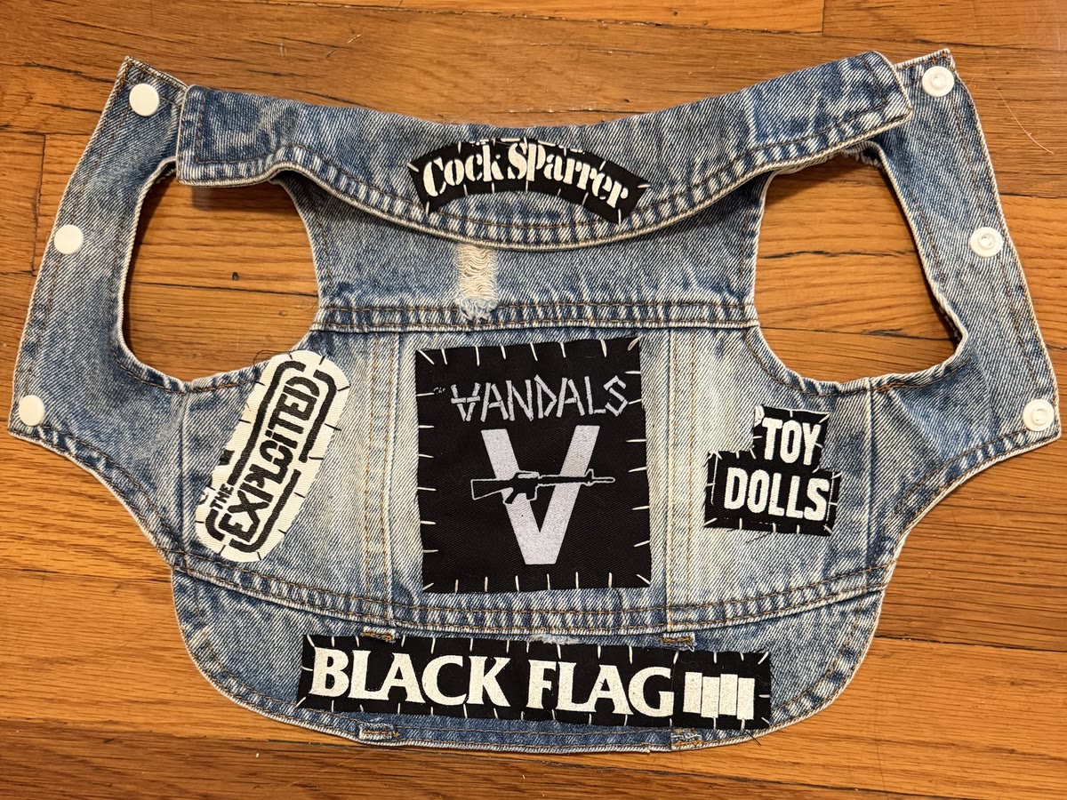 The Old School vest laid flat: plain light denim with a Vandals back patch, a Cock Sparrer strip at the collar, Exploited and Toy Dolls patches, and a Black Flag strip across the hem